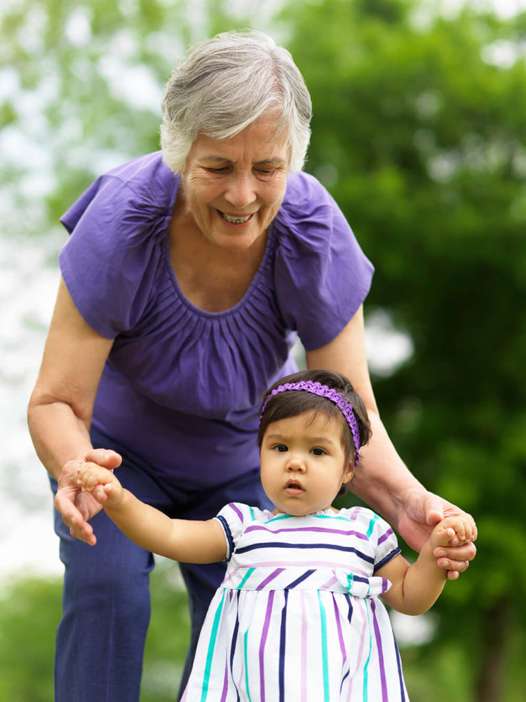 Older woman holding hands with a walking child